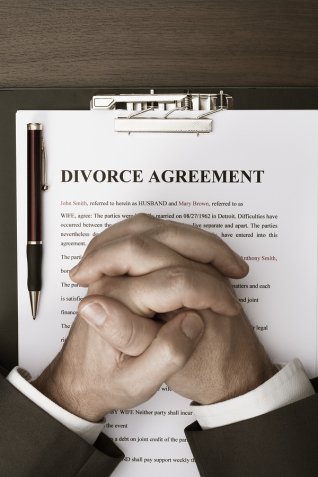 A man folding his hands on top of a divorce agreement that his divorce lawyer in Nevada helped him with.